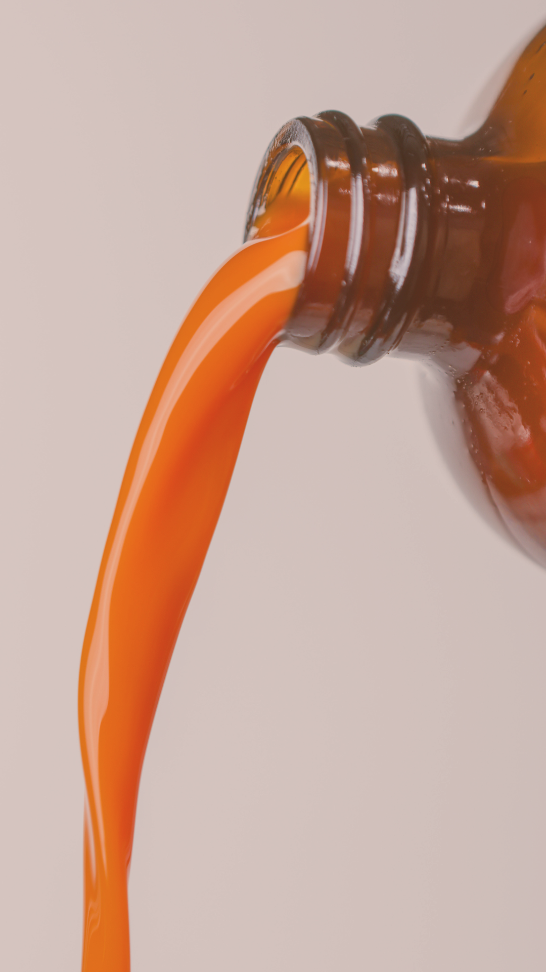 Liquid supplement pouring from amber glass bottle